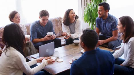 Junge-Erwachsene-Freunde-um-einen-Tisch-in-einem-Café-im-Gespräch