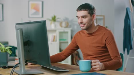 Portrait-of-Handsome-Confident-Man-Working-on-a-Personal-Computer-from-Home.-In-Cozy-Bright-Living-Room-Man-Browses-Through-Internet.