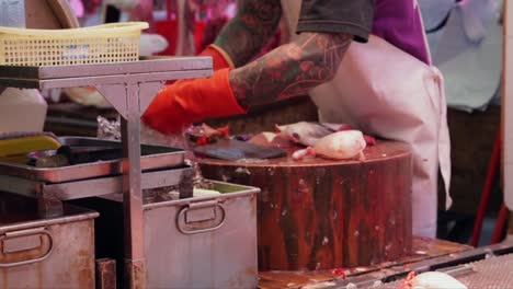 butcher-at-work,-slicing-and-packaging-fish-on-a-chopping-block-at-a-meat-market