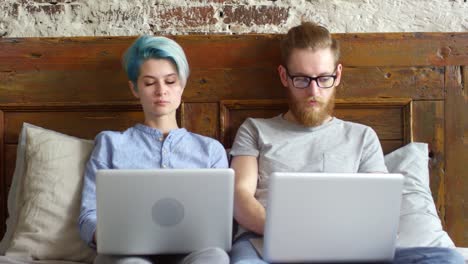 Pareja-con-computadoras-portátiles-trabajando-desde-casa