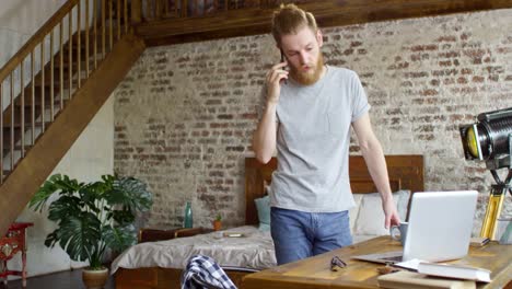 Hipster-Mann-am-Telefon-in-Loft-Wohnung