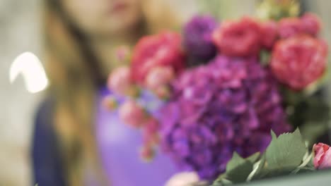 Young-woman-florist-sniffing-a-beautiful-bouquet-of-flowers.-Pretty-girl-holding-a-bunch-of-flowers-at-flower-shop.-Focus-on-flower-bouquet.