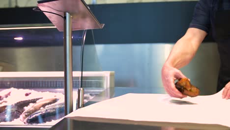 seller-wrapping-fish-into-paper-at-seafood-shop