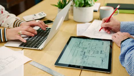 Male-And-Female-Architects-Working-On-Plans-In-Their-Studio