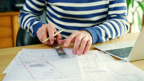 Architect-Working-On-Construction-Design-Blueprints-At-His-Desk