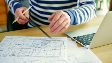 Architect-Working-On-Construction-Design-Blueprints-At-His-Desk