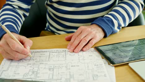 Architect-Working-On-Construction-Design-Blueprints-At-His-Desk