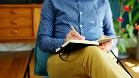 Casual-Businessman-Sitting-On-Chair-And-Writing-Notes-In-A-Journal