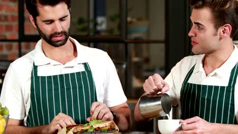 Smiling-waiter-and-barista-discussing-together