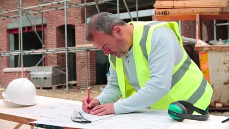 Trabajador-de-construcción-en-sitio-de-construcción-revisando-planos