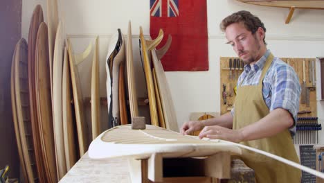 Hombre-construyendo-tabla-de-surf-personalizada-en-el-taller-filmado-en-la-cámara-roja