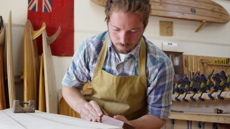 Man-Shaping-Custom-Surfboard-en-el-taller-filmado-en-la-cámara-roja