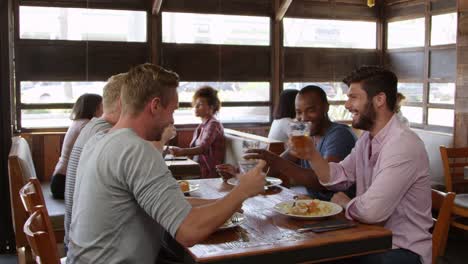 Cuatro-amigos-hacer-un-brindis-en-una-mesa-en-un-restaurante,-un-disparo-de-R3D