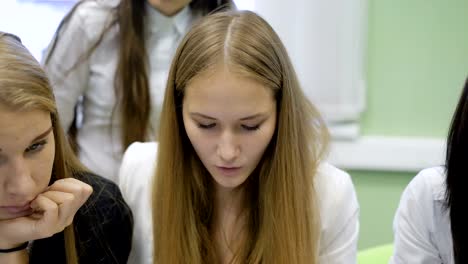 Close-up-of-members-of-business-team-preparing-the-presentation-of-their-startup.-Two-young-fair-haired-and-one-dark-haired-girls-sitting-at-the-desk-and-carefully-looking-at-laptop