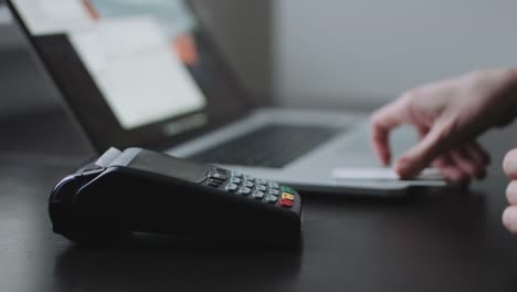 Woman-uses-credit-card-terminal-in-office.