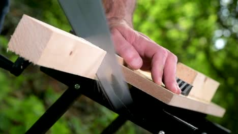 Carpenter-sawing-a-wooden-square-with-a-wood-saw