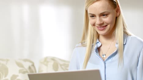 Close-up-of-a-Young-Beautiful-Woman's-Face,-She-Works-on-a-Laptop,-in-a-Light-Environment.