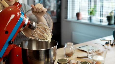 Joven-atractivo-añadiendo-los-ingredientes-en-el-recipiente-y-encender-el-mezclador.-Hembra-mezcla-de-masa-para-hornear