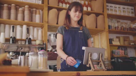 Weibliche-Deli-Shop-Kasse-Einlesen-Karte-auf-digitale-Tablet-Reader