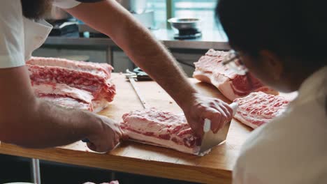 Metzger,-einem-Kollegen-zeigen,-wie-Sie-ein-Stück-Fleisch-mit-Haut