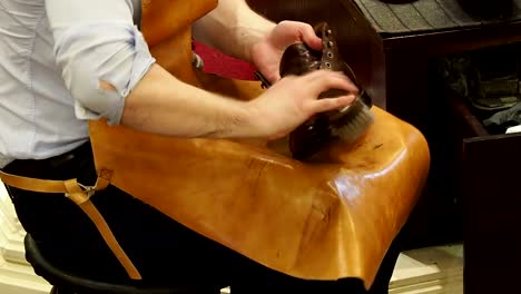 Shoe-shiner-polishes-the-boots-of-brown-leather-with-a-special-brush
