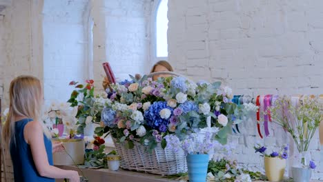 Two-women-florists-making-large-floral-basket-with-flowers-at-flower-shop