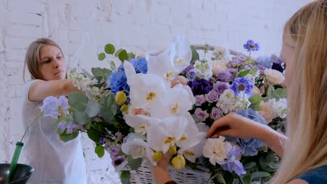 Zwei-Frauen-Floristen-machen-große-Blumenkorb-mit-Blumen-im-Blumenladen