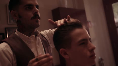 Hipster-hairdresser-styling-young-man's-hair-at-old-fashioned-barber-shop