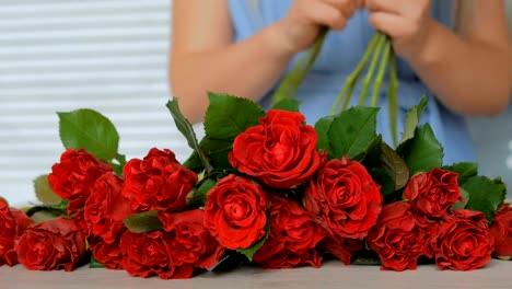 4-shots.-Professional-florist-preparing-red-roses-for-bouquet-at-workshop