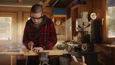 Young-gritty-woman-sawing-wood-in-workshop