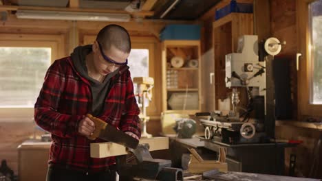 Young-gritty-woman-sawing-wood-in-workshop-,-sideways