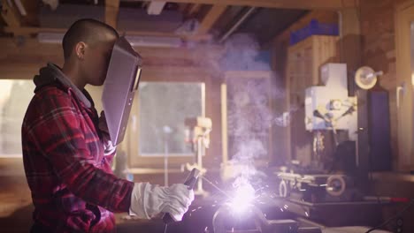 Beautiful-woman-with-short-hair-is-welding-metal-in-a-workshop