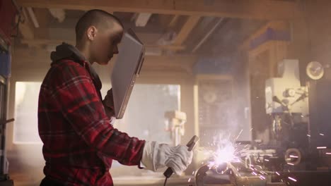 Portrait-of-young-powerful-woman-welding-in-workshop