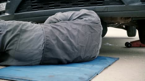 Mecánico-trabajando-por-debajo-de-un-coche