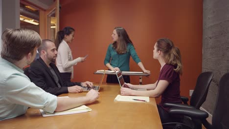 Woman-leading-a-small-business-meeting-when-an-intern-brings-her-a-note-and-she-leaves