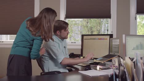 Colleages-gathered-around-a-computer-in-a-bright-office-and-reading-charts