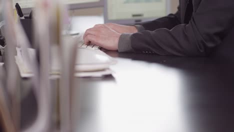 Close-up-of-a-frustrated-business-man-entering-data-into-a-computer