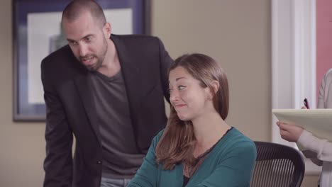 Colleages-and-an-intern-gathered-around-a-computer-in-a-bright-office-and-working