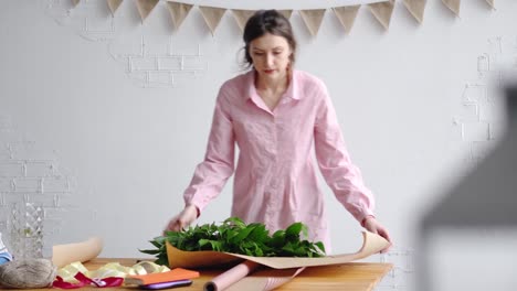 Florist-stellt-Grüns-auf-dem-Papier-um-einen-Blumenstrauß-zu-erstellen.-Blumengeschäft