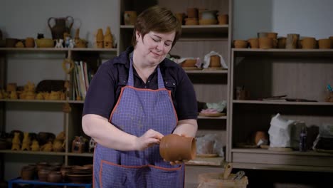 pottery-master-wipes-with-a-damp-sponge-clay-pot-in-the-workshop-where-she-works,-the-woman-made-the-dishes-for-sale