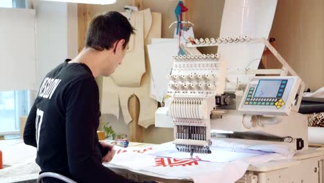 Young-man-is-embroidering-pattern-on-computerized-machine