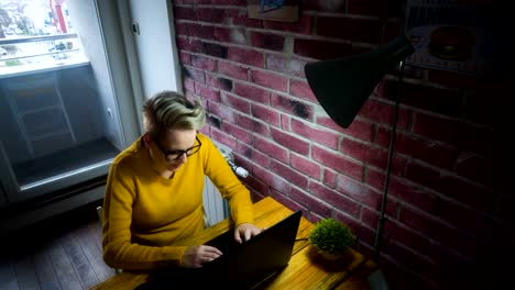 Attractive-young-woman-working-at-the-desk-with-a-laptop-in-home-office.