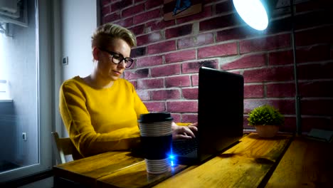 Attractive-young-woman-working-at-the-desk-with-a-laptop-in-home-office.