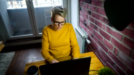 Attractive-young-woman-working-at-the-desk-with-a-laptop-in-home-office.