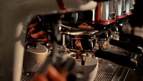 Close-up-of-barista-steaming-milk-at-coffee-machine-in-café