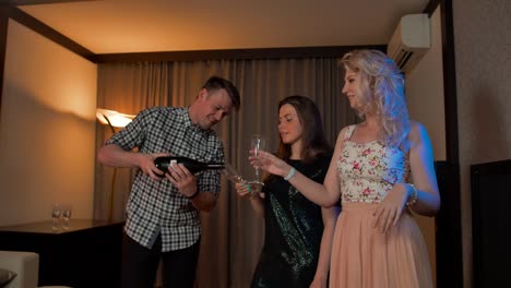 Young-guy-pouring-champagne-in-glasses-of-two-sexy-ladies