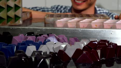 Cheerful-confectioner-examining-handmade-candy-at-his-kitchen