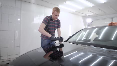 Man-sedulously-polishing-bumper-of-car