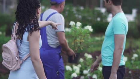 Jardinero-de-altura-muestra-flores-a-los-clientes-en-el-jardín