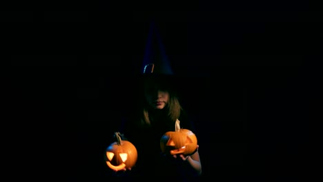 Girl-wearing-black-witch-hat-holding-jack-o'-lanterns